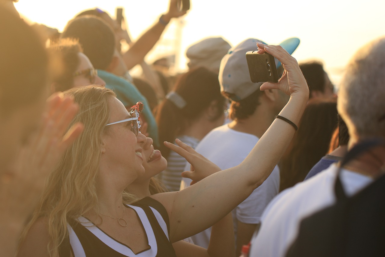 Feiernde junge Menschen. Eine Person macht ein Selfie von sich. Es ist ein helles Bild und im Freien. © Pixabay/OrnaW